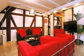 Una sala moderna con un sofá rojo, un televisor de pantalla plana y una planta grande en maceta.