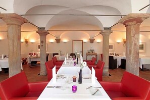 A restaurant with white tables, red chairs, and stone columns.