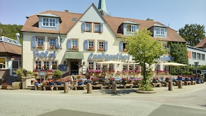 Ein Hotel im traditionellen europäischen Baustil, mit einem markanten Kirchturm und einem Innenhof mit Außenplätzen.