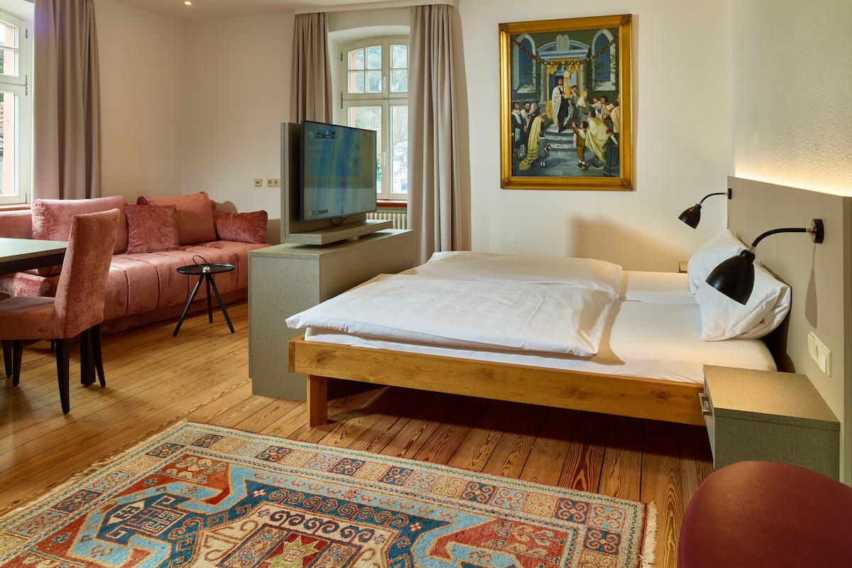 Une chambre d’hôtel avec un lit, un canapé, une télévision et un tableau au mur.