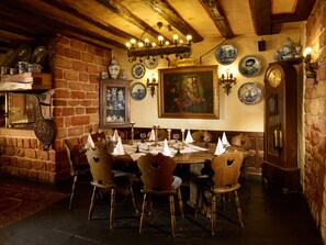 Comedor con pared de ladrillo, techo de madera y mesa dispuesta para seis personas con sillas.