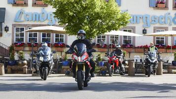 En rad motorcyklar parkerade framför en byggnad med en skylt som visar texten ”Landgasthof”.
