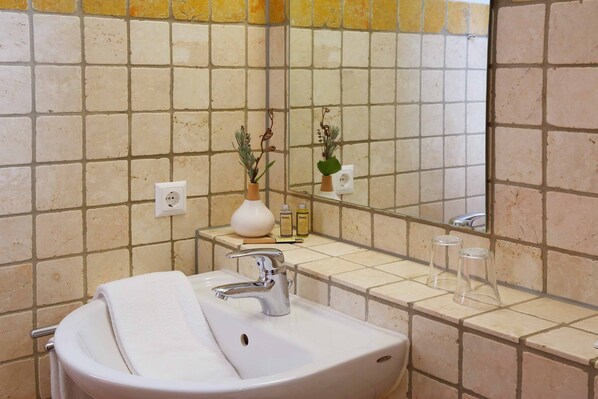 A bathroom with a white sink, a mirror, and a tiled wall.