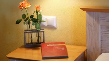 A bedside table with a vase of roses and a book titled "Frankenstein".