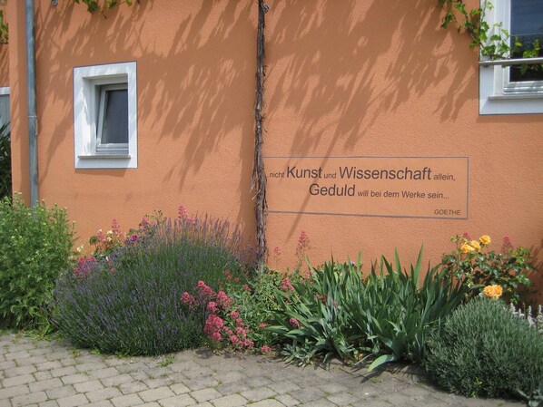 Un edificio con una placa que cita a Goethe, rodeado de diversas plantas y una pequeña ventana.