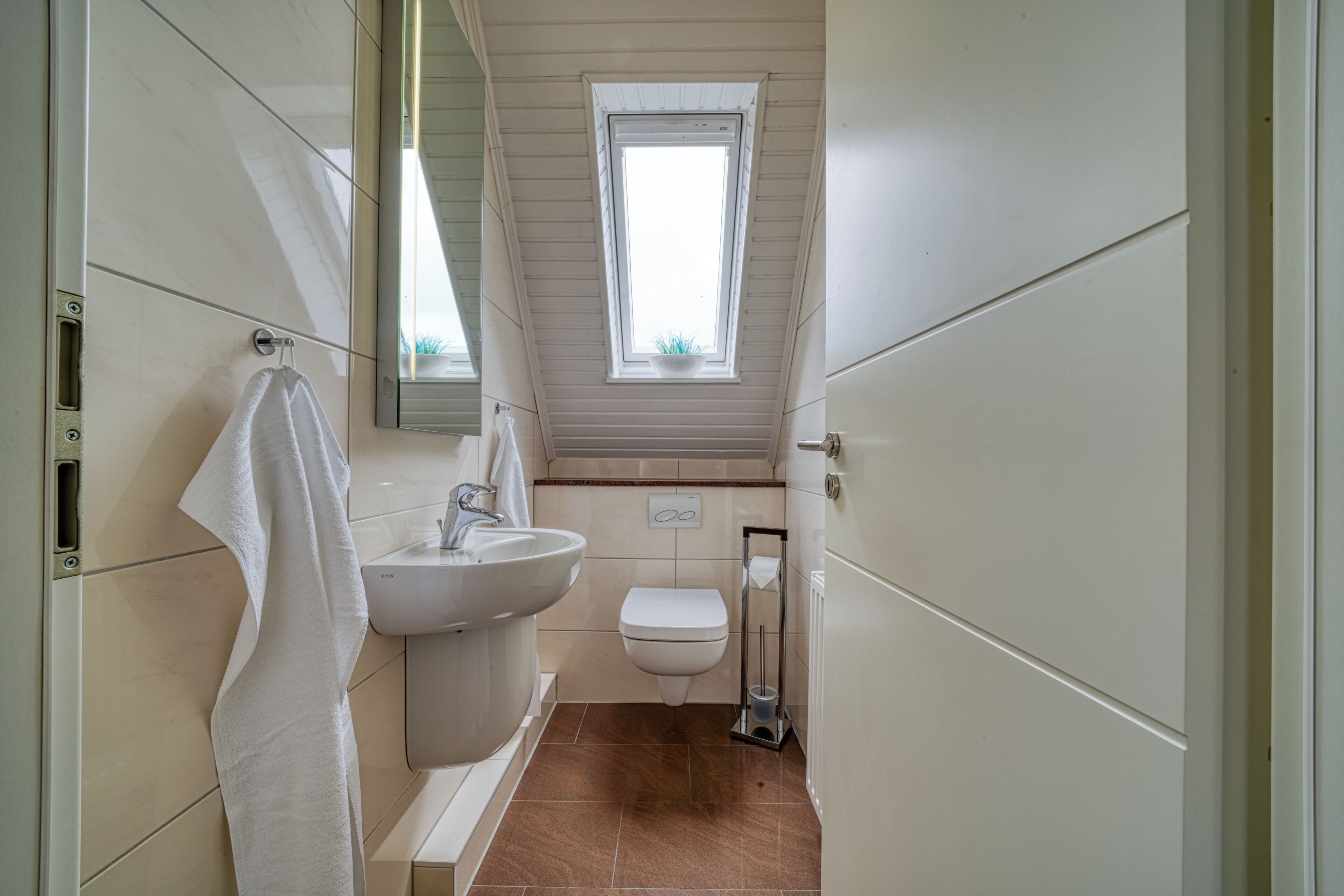 A bathroom with a sink, toilet, and window.