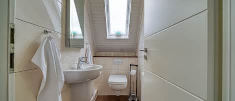 A bathroom with a sink, toilet, and window.