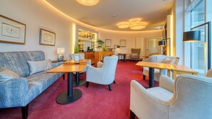 Eine moderne Hotelhalle mit Barbereich, Sitzgelegenheiten und gerahmten Kunstwerken an den Wänden.