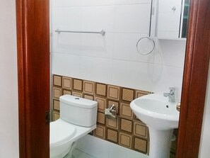 Un baño con inodoro, lavamanos y toallero.