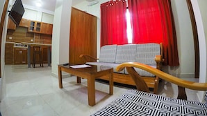 A living room with a sofa, a wooden coffee table, and a TV mounted on the wall.