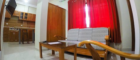 Un salon avec un canapé, une table basse en bois et un téléviseur fixé au mur.