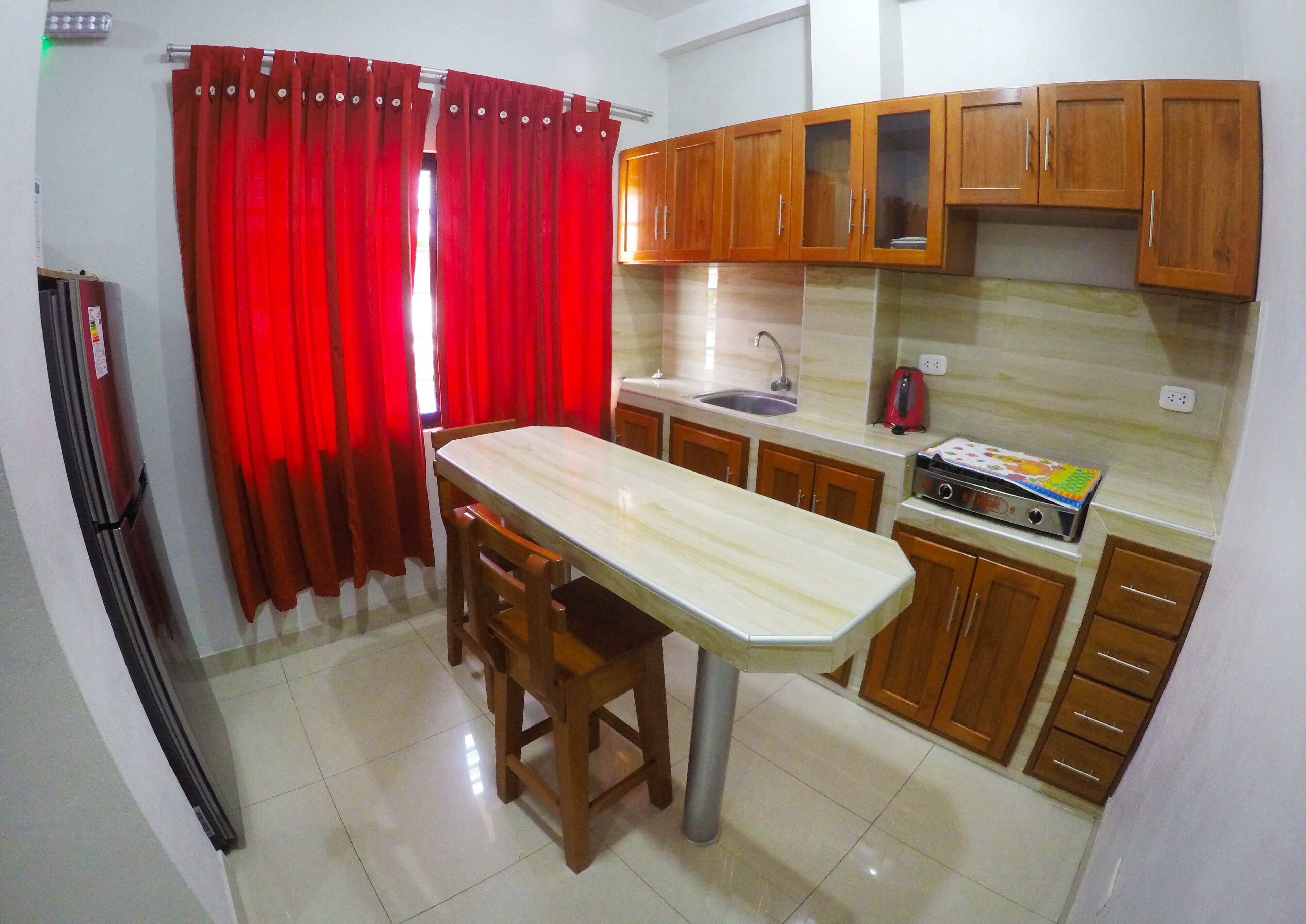 Una cocina compacta con una isla central, armarios de madera, un refrigerador y un tostador.