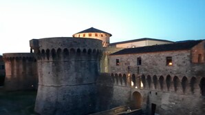 Una fortalesa de pedra històrica amb una torre central rodona i diversos passadissos en arc.