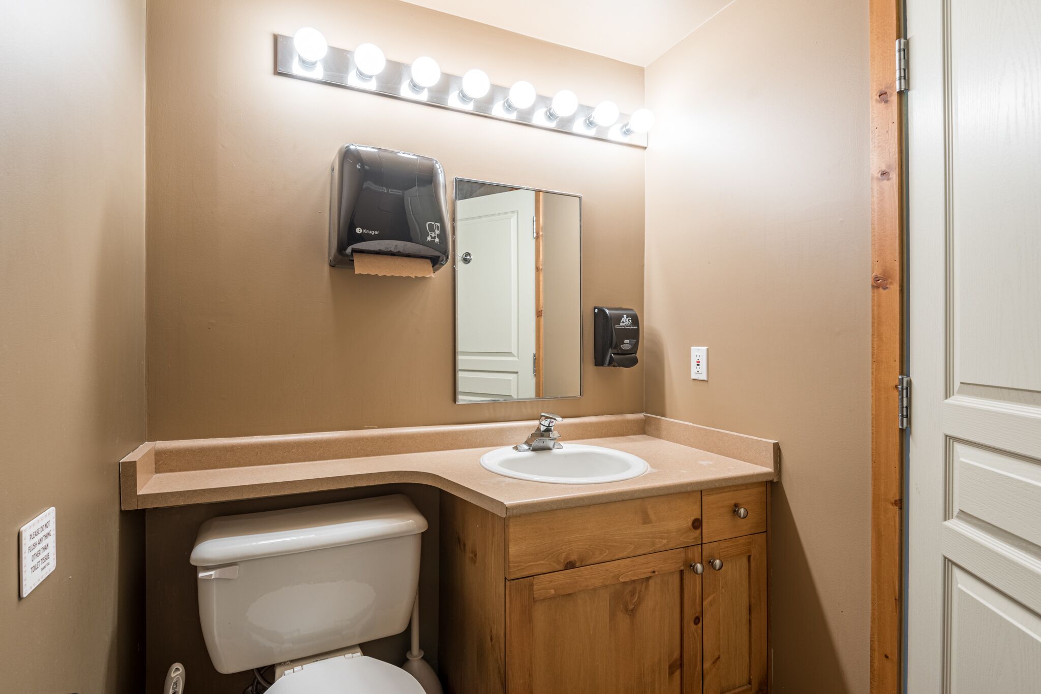 A bathroom with a sink, mirror, vanity, and toilet.