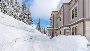 A snow-covered road leading to a building with multiple windows and a snow-covered roof. - Newly Renovated Ground Floor Creekside Studio Condo - Pet Friendly too!  (Silver Star Mountain)