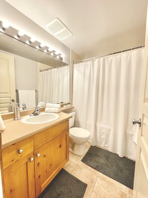 A bathroom with a vanity, sink, mirror, and toilet.