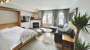 A modern hotel room with a large bed, a fireplace, a sofa, a small table, and a TV. - Newly Renovated Ground Floor Creekside Studio Condo - Pet Friendly too!  (Silver Star Mountain)