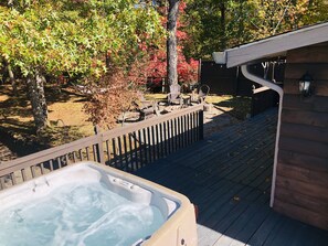 A hot tub on a wooden deck with a wooden fence and trees in the background. - The AMAZING VIEW at Pop’s Cottage (Bryson City)