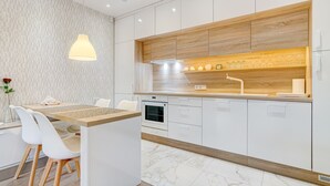 A modern kitchen with white cabinets, a wooden countertop, and a built-in oven. - Happy InnSide in central. Self check-in + free parking (Vilnius)
