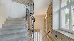 A staircase with stone steps and a metal railing, leading to a room with a brick wall and a window. - Happy InnSide in central. Self check-in + free parking (Vilnius)