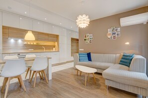 A modern kitchen with white cabinets, a wooden countertop, and a dining area with a white table and chairs.