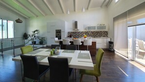 Une cuisine moderne avec des meubles blancs, un îlot central et un coin repas comprenant une table et des chaises.