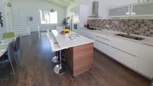 Une cuisine moderne avec des armoires blanches, un îlot central en bois et une grande fenêtre.