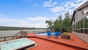 A wooden deck with a hot tub, two blue chairs, and a small table with a planter. - Pocono Lakefront Paradise, dock, hot tub, private pool and tennis court (pocono summit)