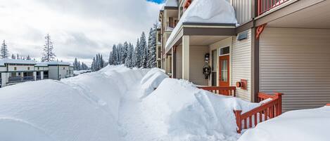 A snow-covered hotel with a red railing and a snow-covered driveway.
