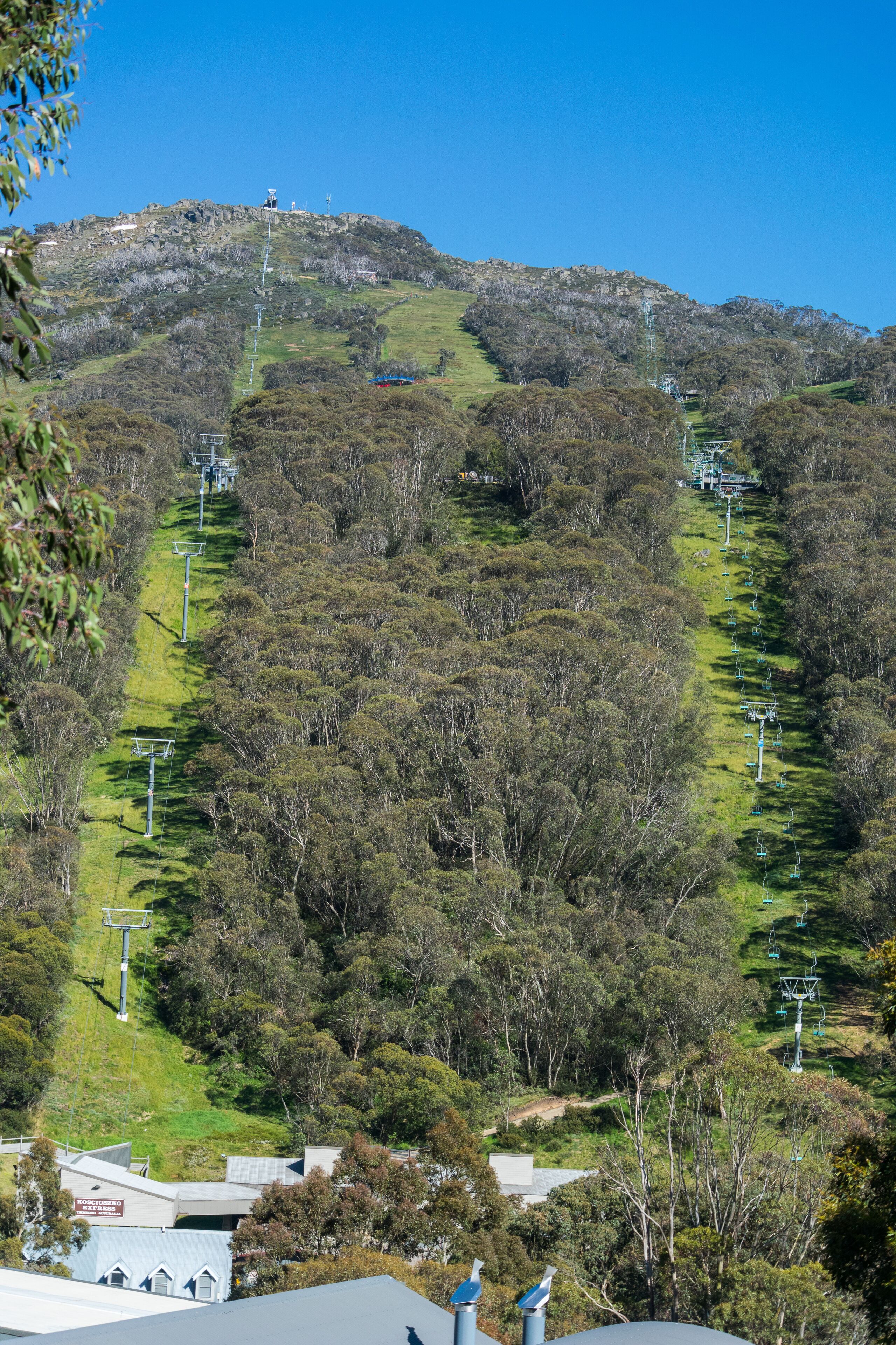 Un paysage vallonné sous un ciel dégagé, un sentier qui monte la colline et un bâtiment doté de panneaux solaires à sa base.