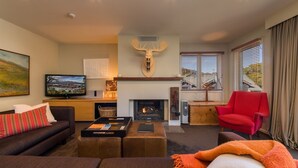 Una sala de estar con chimenea, televisor, una silla roja y un sofá.
