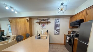 A kitchen with wooden cabinets, a central island, a microwave, and a refrigerator.