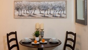 A dining table with two chairs, a painting above the table, and a mirror on the wall. - Walk to Beach, Restaurants  & Attractions (Nassau)