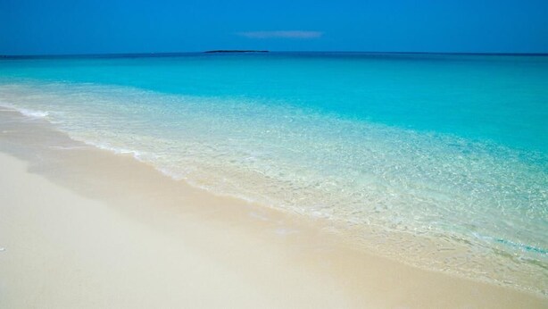 A beach with clear turquoise water and a sandy shore. - Walk to Beach, Restaurants  & Attractions (Nassau)