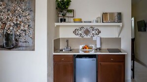 A compact kitchen with a dishwasher, a microwave, and a refrigerator. There is a shelf above the sink with a bowl and a plant. - Walk to Beach, Restaurants  & Attractions (Nassau)