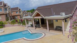 A residential building with a swimming pool, outdoor seating, and a covered patio area. - Tropical Luxury Dreams Ocho Rios (Ocho Rios)