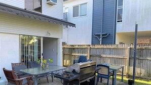 An outdoor patio with a grill, chairs, and a table. - Fully-furnished, family & pet-friendly home 100m the water.. (wynnum)