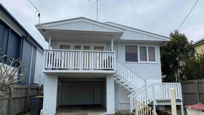 A two-story house with a covered garage, a balcony, and a staircase leading to the upper floor. - Fully-furnished, family & pet-friendly home 100m the water.. (wynnum)