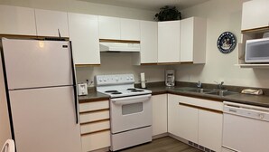 A kitchen with white cabinets, a stove, a refrigerator, a microwave, and a sink.