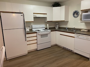 Kitchen features a refrigerator, stove, and dishwasher, with cabinetry and a microwave.