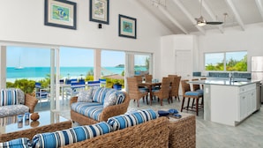 A spacious living area with wicker furniture, a dining set, and a kitchen island. - Coconut Beach Villa! BEACHFRONT Sapodilla! Private Pool! Luxury Family Friendly! (Providenciales)