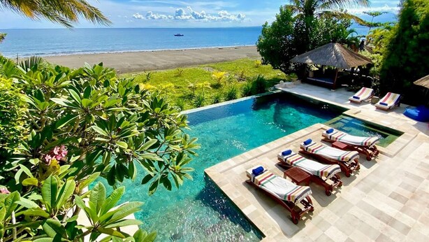 A pool area with lounge chairs and a view of the beach.