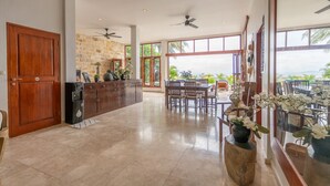 A spacious kitchen with a stone wall, wooden cabinets, and a dining area with a view of the ocean.