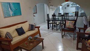 A living room with a sofa, coffee table, and dining area with chairs. - Casa em Porto de Galinhas. 450m aproximado da praia. Piscina com apoio coberto (Porto de Galinhas)