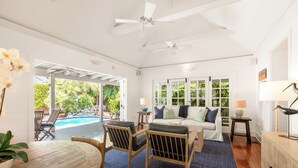 Un vaste espace de vie avec une piscine, des meubles en bois et un ventilateur de plafond.