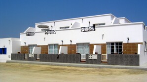 Um edifício moderno com telhado plano, várias janelas e base de concreto.