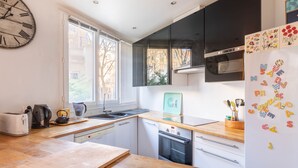 Una cocina moderna con encimera de madera, horno empotrado, microondas y refrigerador con imanes.