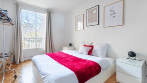 Un dormitorio moderno con una cama grande, una mesita de noche, un armario y una ventana con cortinas.