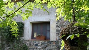 Un bâtiment rustique en pierre, doté d’une fenêtre et d’une petite structure en bois.