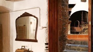 Un intérieur rustique avec un escalier en pierre, une porte en bois et un miroir sur un mur blanc.
